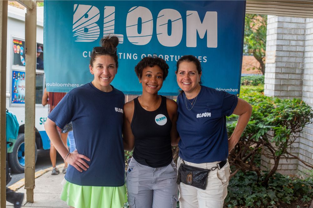 Jesse Garchik, Desiree Coles, and Carlee Chiate in front of a BLOOM sign